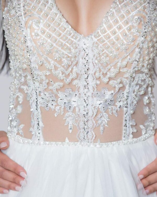 Εντυπωσιακό νυφικό με ολοκέντητο μπούστο με πέρλες και swarovski, με διαφάνεια soleil και ανοιχτή πλάτη.  Φούστα από μεταξωτό τούλι.