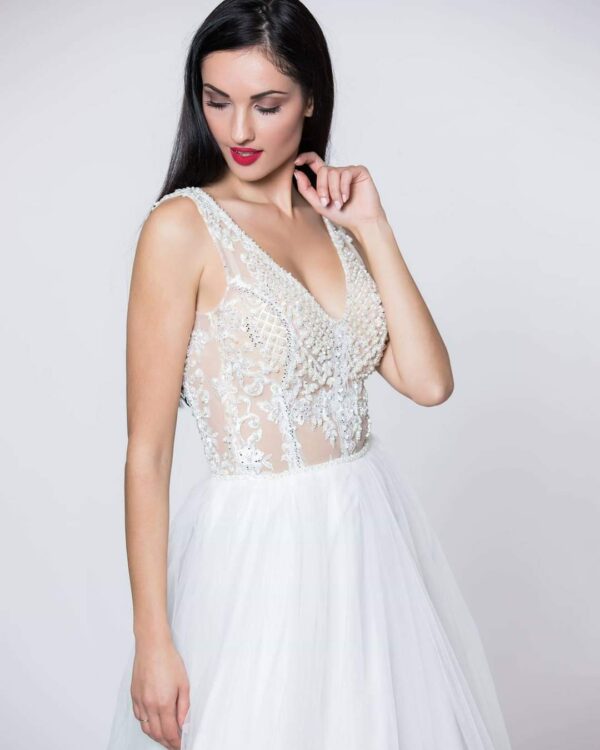 Εντυπωσιακό νυφικό με ολοκέντητο μπούστο με πέρλες και swarovski, με διαφάνεια soleil και ανοιχτή πλάτη.  Φούστα από μεταξωτό τούλι.