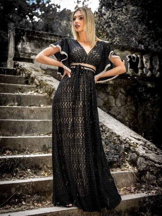 Maxi φόρεμα με δαντέλα σε μαύρο, εσωτερικά μπεζ ελαστική επένδυση, με μπούστο V και ίδια πλάτη, πλούσιο βολάν στο μανίκι χρυσή ζώνη. Ίσια γραμμή. Ελληνικής ραφής