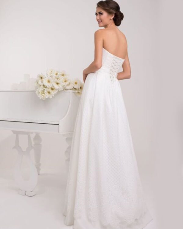 Στράπλες  νυφικό σε Άλφα γραμμή με υπέροχο δέσιμο στη μέση με πλούσιο φιόγκο. Σε ανάγλυφο γαλλικό σατέν. Υπέροχο δέσιμο με κορδέλα στην πλάτη σε στυλ κορσέ.