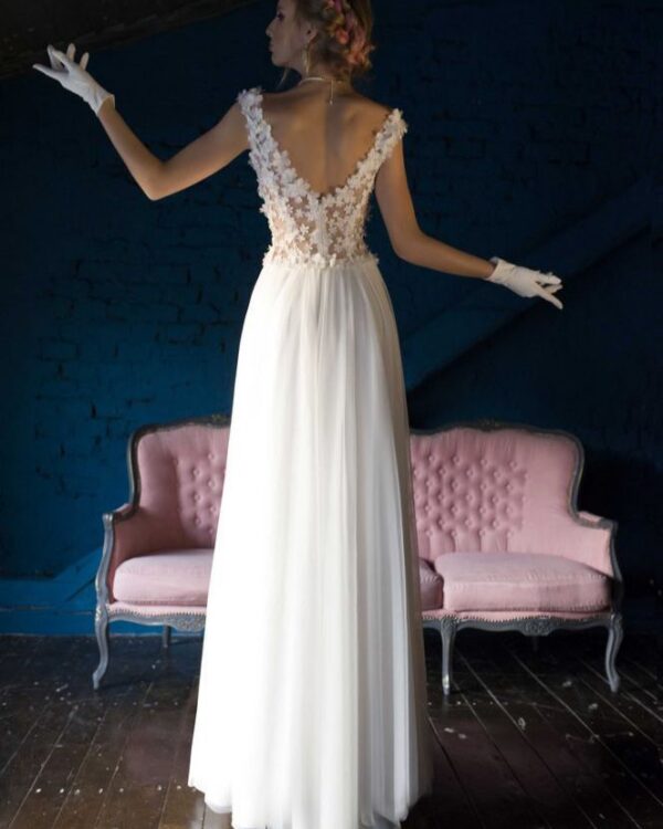 Μεταξωτό νυφικό σε ίσια γραμμή , με φούστα από μεταξωτή μουσελίνα. Με υπέροχο ολοκέντητο μπούστο με 3D μεταξωτά χειροποίητα λουλούδια, που καταλήγει σε βαθύ V στην πλάτη και το μπούστο. Αέρινη γραμμή. Ελληνικής ραφής