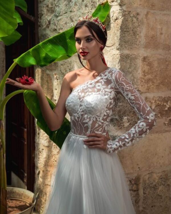 Εκκεντρικό νυφικό με ολοκέντητο μπούστο με γαλλική δαντέλα διαφάνεια soleil, με έναν ώμο και στενό μανίκι δαντέλα. Πλούσια φούστα από γαλλικό τούλι.