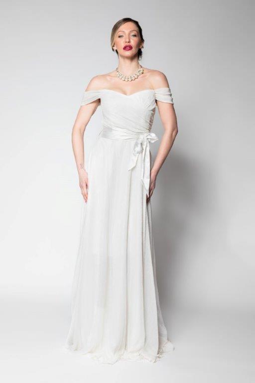 Νυφικό φόρεμα lurex έξωμο, με ριχτό μανικάκι στο μπράτσο, υπέροχο μπούστο σταυρωτό με σατέν ψιλόμεση ζώνη και πλούσια φούστα. Ελληνικής ραφής