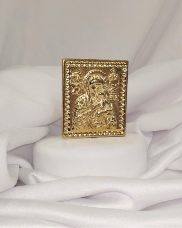 Μπομπονιέρα με λευκό βότσαλο και επίχρυσο διακοσμητικό με την Παναγία. Παραδίδεται έτοιμη δεμένη με κουφέτα. Διαστάσεις  ύψος 10εκ. πλάτος 8εκ. Ελάχιστη παραγγελία 20 τεμάχια.