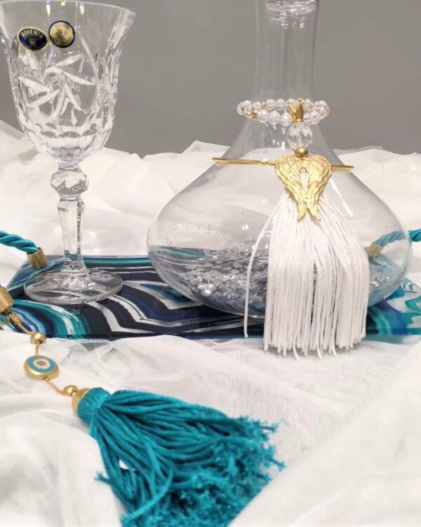 Σετ κουμπάρου σε κρύσταλλο Βοημίας με επίχρυσο στολισμό Tresento. Το σετ περιλαμβάνει περίτεχνο δίσκο με σμάλτο και πλεξιγκλάς, ιδιαίτερη μποτίλια κρασιού και ποτήρι από κρύσταλλο Βοημίας, διακοσμημένο με επιχρυσωμένο 24 καρατίων στολίδι Tresento με φτερά αγγέλου, με πέταλο, γαλάζια φούντα και μεταξωτό κορδόνι. Όλα είναι χειροποίητα και κατασκευασμένα στην Ελλάδα.