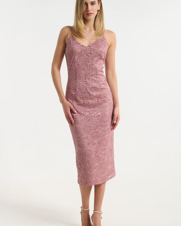 Woman in a pink lace midi dress standing against a light background, wearing beige heels.