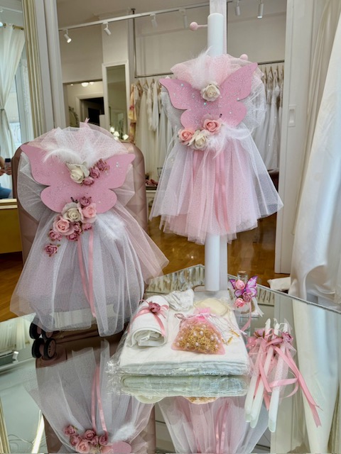 Display of pink butterfly-themed dresses with tulle skirts and rose accents in a bridal boutique window.