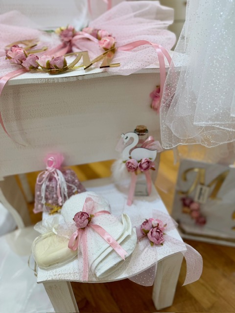 oloklhrwmeno paketo baptishs me ksulino mpoudouar(4) Pastel wedding décor with white gift boxes tied with pink ribbons, rose accents, lace veil, and a small white swan figurine.
