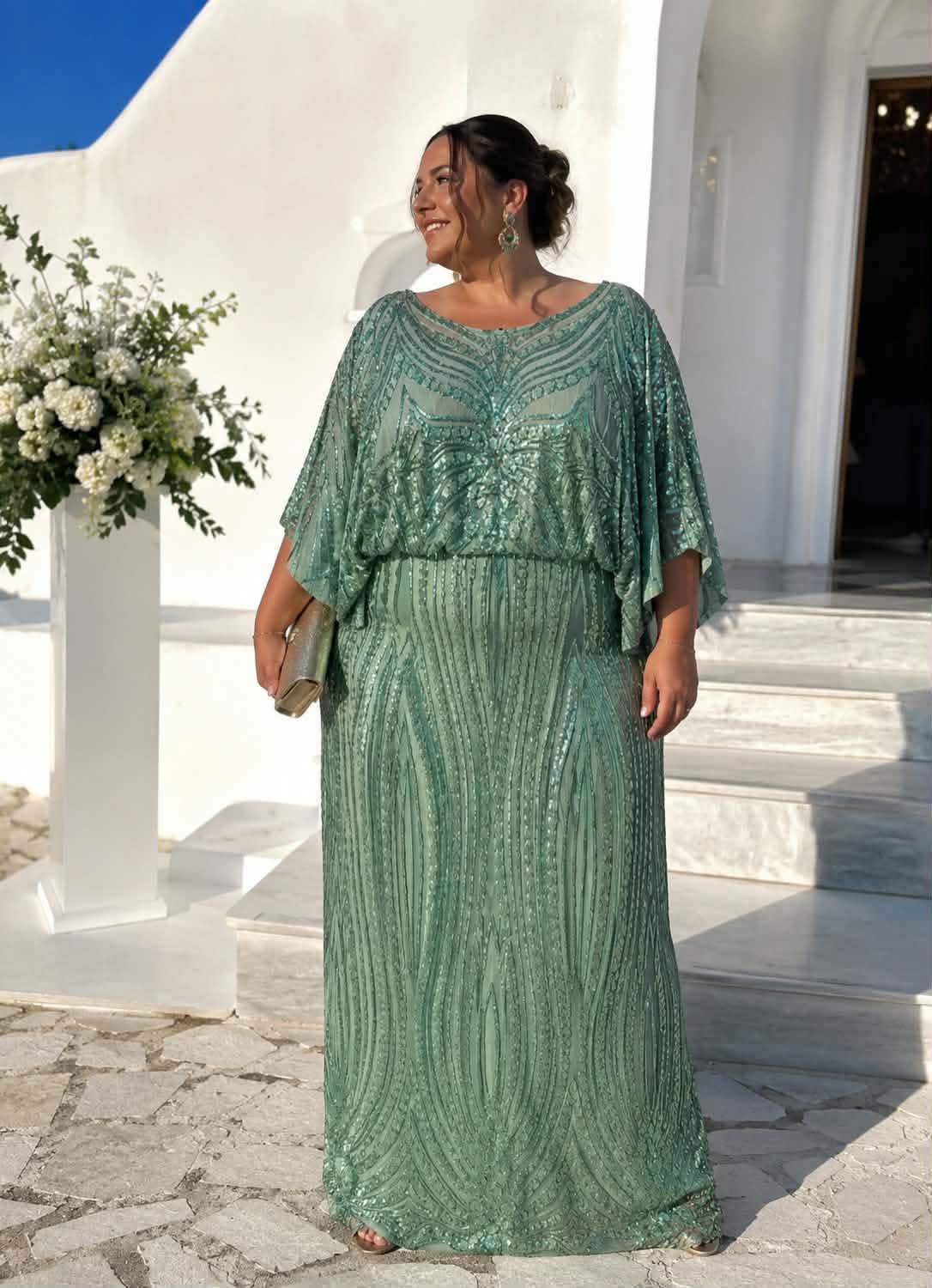 maxi forema me gewmetrikes pagietes kai aerina manikia(3) Woman in a mint-green, beaded gown posing outdoors beside white architecture and a flower arrangement, smiling and wearing statement earrings and a clutch