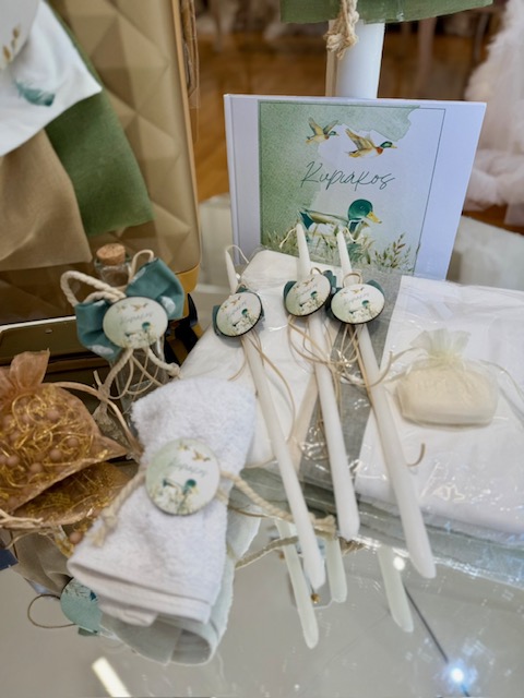 oloklhrwmeno paketo baptishs me thema th xhna(4) Decorative gift display with white taper candles on twine, round bird-themed tags, folded towels, soap, and a blue-green greeting card in the background.