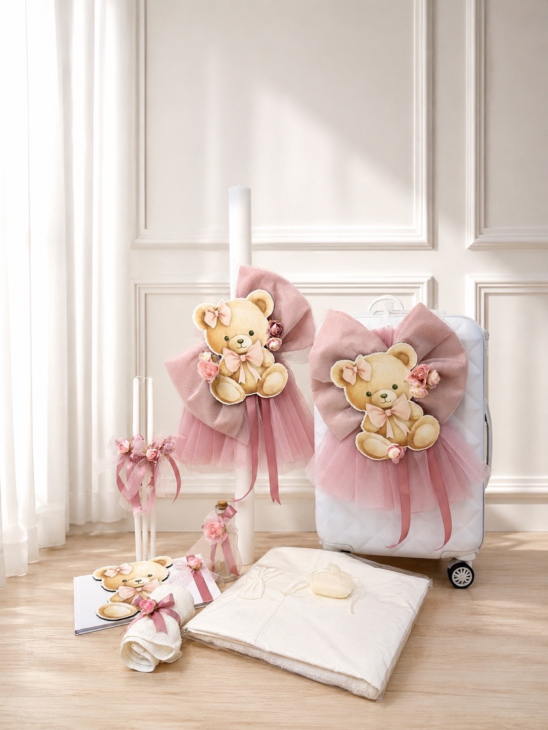 oloklhrwmeno paketo baptishs me thema to arkoudaki(1) Pastel pink teddy bear decorations with bows and tulle draped on a white suitcase in a bright room.