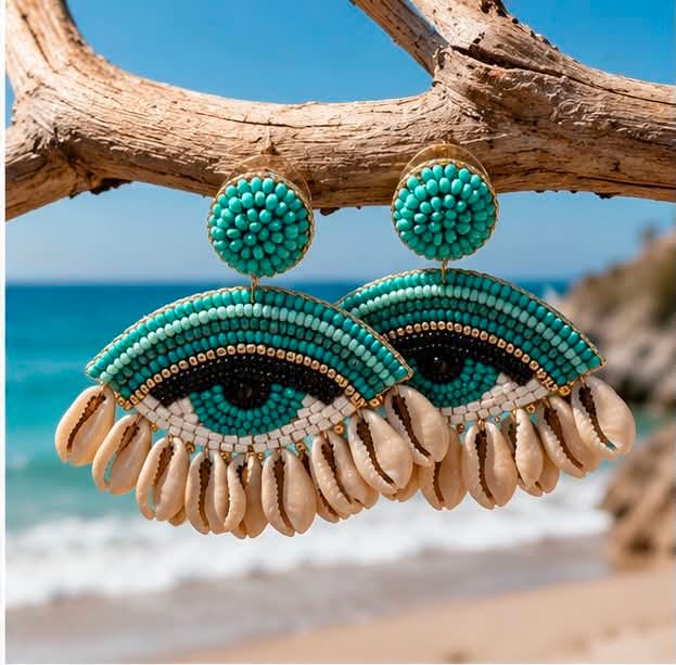 xeiropoihta skoularikia mati me xantres kai koxulia(1) Turquoise beaded earrings shaped like eyes hang from a weathered branch at the beach.