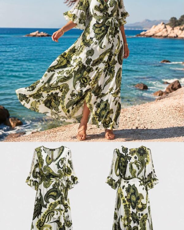 Woman in a white and green paisley wrap maxi dress walking along a rocky beach by the ocean, wind in her hair.