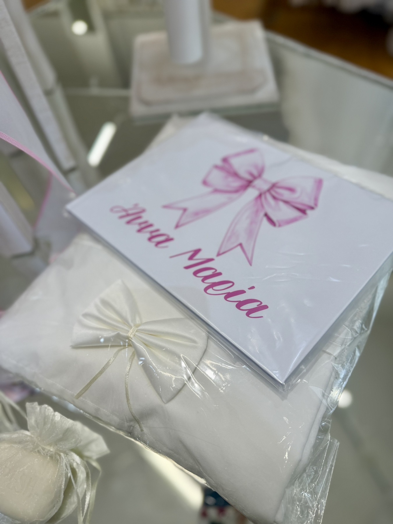 oloklhrwmeno paketo baptishs me ksulino mpoudouar me thema thn kamhlopardalh(2) White gift box wrapped in white paper with a pink ribbon bow, among other wrapped presents.