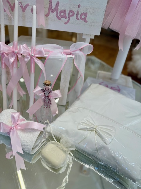 oloklhrwmeno paketo baptishs me ksulino mpoudouar me thema thn kamhlopardalh(5) Pastel pink-and-white wedding décor on a glass surface with ribbons, candles, and neatly wrapped gifts