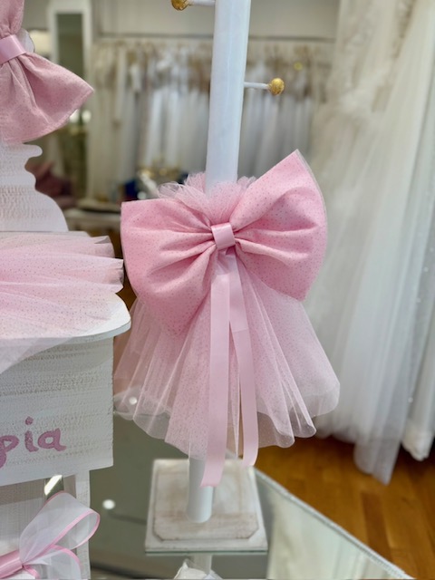 oloklhrwmeno paketo baptishs me ksulino mpoudouar me thema thn kamhlopardalh(4) Pink tulle bow tied around a white display pole in a bridal shop.
