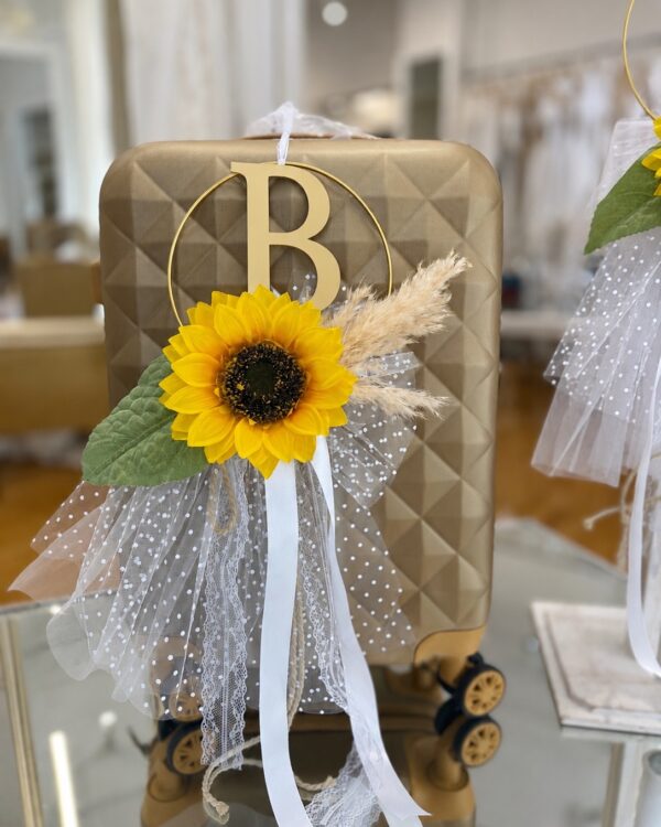 Decorative brown geometric suitcase with a bright sunflower, white lace, and tulle ribbons for a celebration or wedding prop.