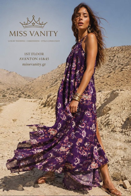 Model in a flowing purple floral maxi dress on desert dunes, promoting MISS VANITY fashion brand. Includes brand text and website on the left.
